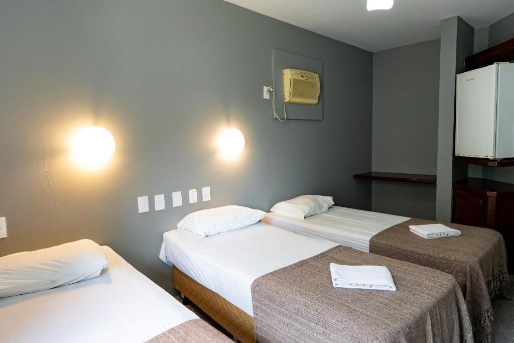 Une chambre d’hôtel avec deux lits, une armoire et un radiateur fixé au mur.
