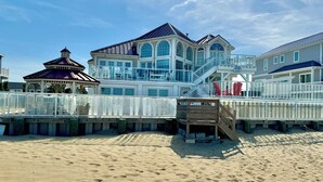 Ein Strandgrundstück mit einem großen Haus, einem Pavillon und einer Holzterrasse.