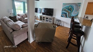 A modern living room with a sofa, a chair, a TV, and a marble artwork. - Acadia Villas!  2A Hunter's Way with EV Charger. (Trenton)