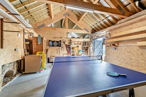A ping pong table in a rustic wooden room with exposed beams and a high ceiling. - 4 Bed in Goodleigh (oc-e29107) (Goodleigh)