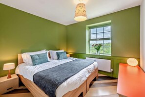 Ein Schlafzimmer mit Bett, Fenster mit Aussicht, Nachttischlampe und Beistelltisch.