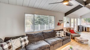 Ein geräumiges Wohnzimmer mit einem großen grauen Sofa, einem Couchtisch und einem Deckenventilator.