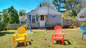A small house with a front porch, a white door, and a mailbox. There are two chairs in the yard. - Family-Friendly Home! Walk to Sea Street Beach (Dennis Port)