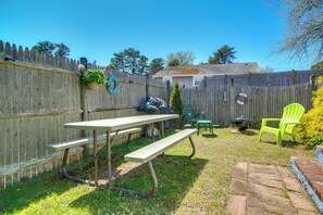 A backyard with a picnic table, green chairs, and a wooden fence. - Family-Friendly Home! Walk to Sea Street Beach (Dennis Port)