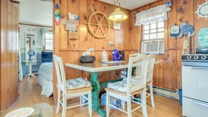 A wooden interior with a dining table, chairs, a clock, and a stove. - Family-Friendly Home! Walk to Sea Street Beach (Dennis Port)