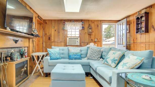 A cozy living room with a sectional sofa, a fireplace, and wooden walls. - Family-Friendly Home! Walk to Sea Street Beach (Dennis Port)