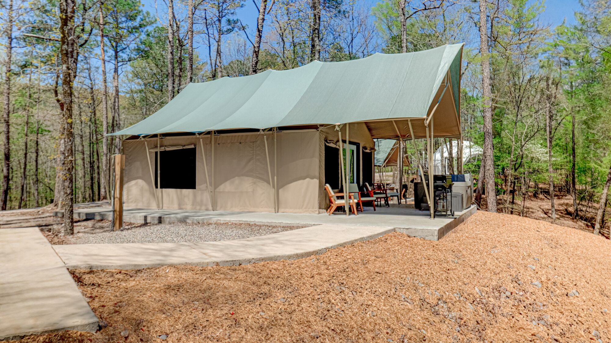 A large, open-air structure with a covered patio area, surrounded by trees.