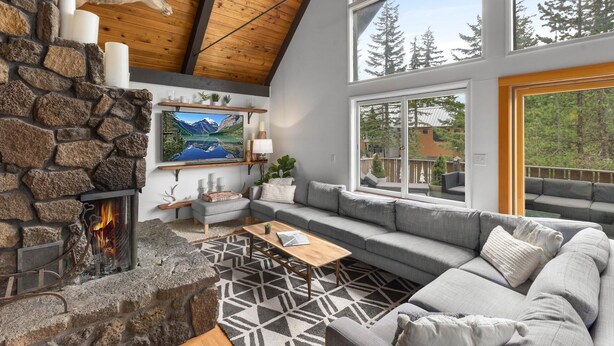 A cozy living room with a stone fireplace, a large TV, and a comfortable seating area with a view of the outdoors.