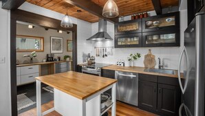 A modern kitchen with wooden beams, stainless steel appliances, and a wooden island.