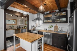 Una cocina moderna con vigas de madera, electrodomésticos de acero inoxidable y una isla central.