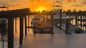 A wooden dock with boats moored at a marina during sunset. - Waterfront Home on the Harbor with a Pool, Boat Dock & Pet Friendly! (Stuart)