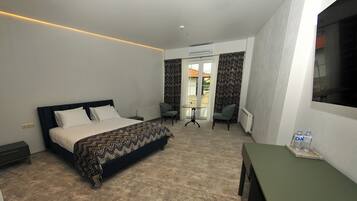 Habitación de hotel moderna con cama, una mesita, dos sillas y vistas al exterior.