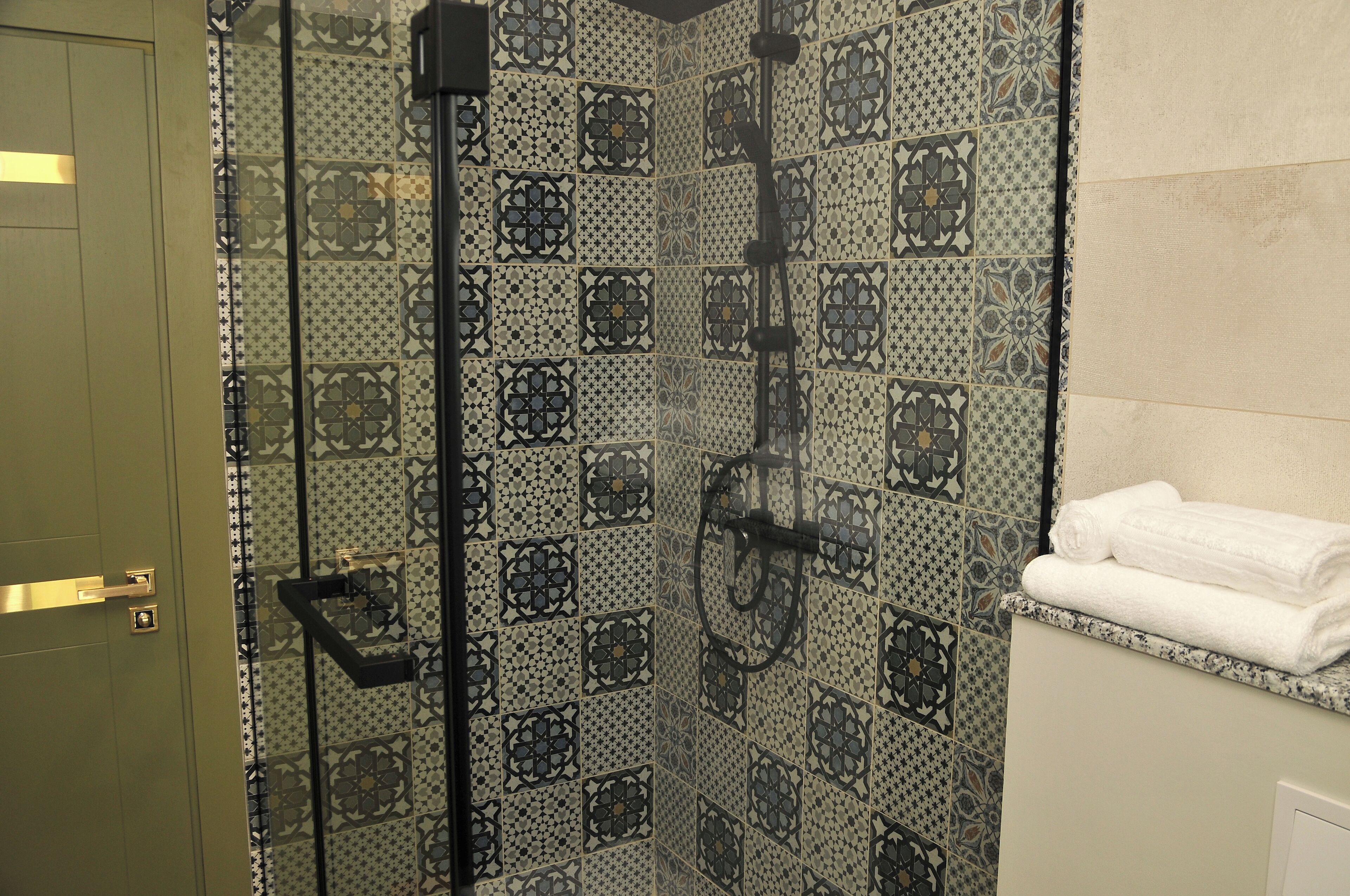 A bathroom with patterned tiles, a towel rack, and a door.