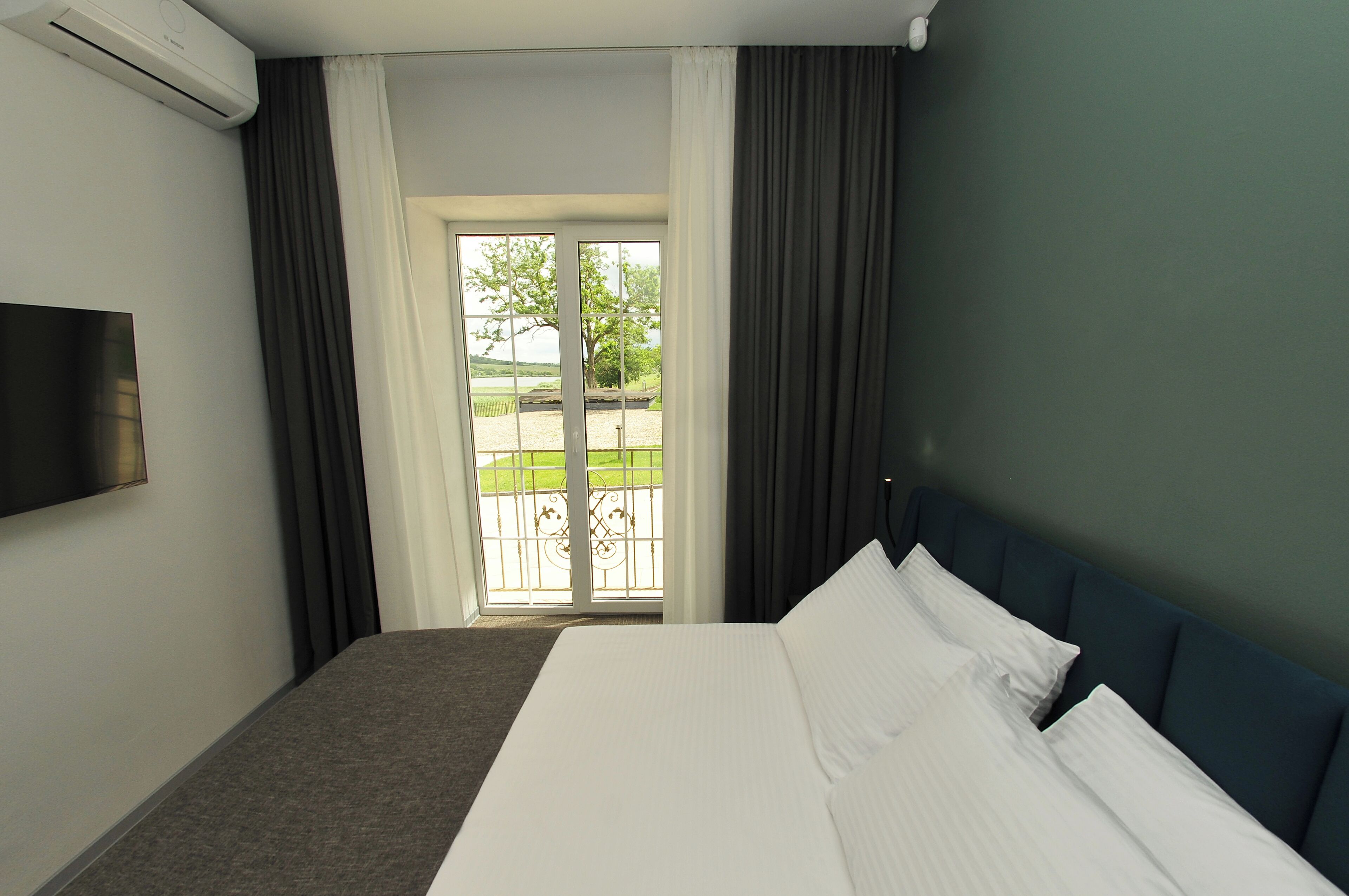 Ein Hotelzimmer mit Bett, Flachbildfernseher und Balkonblick.