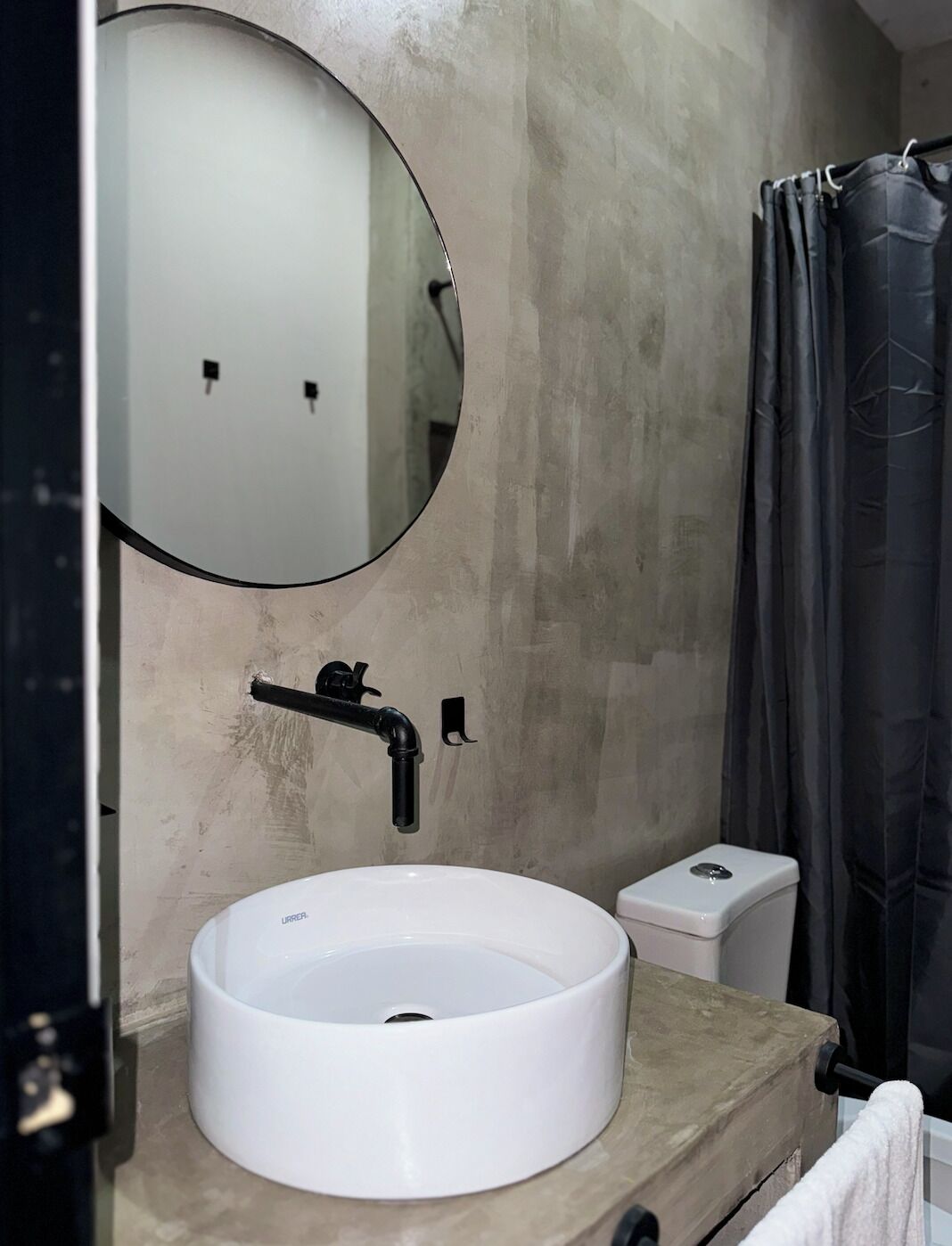 Ein Badezimmer mit einem runden weißen Waschbecken, einem Spiegel und einer Toilette.