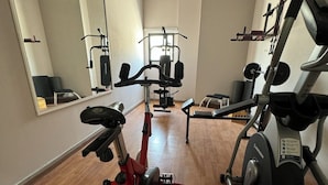 Un gimnasio con equipo cardiovascular, máquinas de pesas y un espejo grande.
