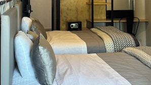 Una habitación de hotel pequeña con cama, un escritorio, estante y televisor instalado en la pared.