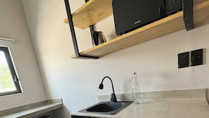Una cocina compacta con lavavajillas negro, un lavamanos y una repisa de madera.