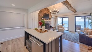 Une cuisine moderne avec un îlot central, un mur en briques et une vue sur la mer.
