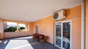 A balcony with a table and chairs, a sliding glass door, and an air conditioning unit. - Bonvie Apartments in Center B4 (Novalja)
