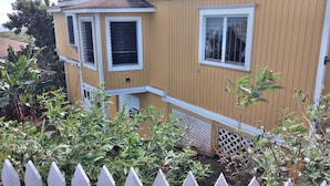 Ein gelbes Haus mit weißem Zaun, einer kleinen Veranda und einem Fenster mit Fensterläden.