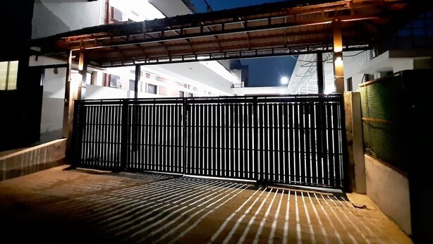 A gated entrance with a metal fence and a covered walkway. - Deep Woods Stay (Kinathukadavu)