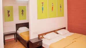 A hotel room with two beds, a wooden floor, and artwork on the wall. - Deep Woods Stay (Kinathukadavu)