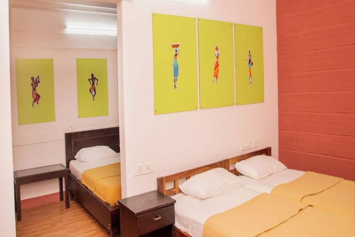 A hotel room with two beds, a wooden floor, and artwork on the wall.