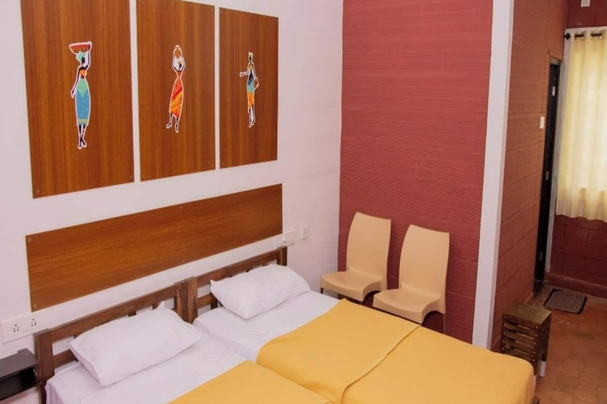 A hotel room with two beds, a wooden headboard, a red accent wall, and three wall-mounted artwork depicting stylized figures.