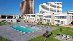A modern hotel with a swimming pool, multiple buildings, and a well-maintained lawn. - Rosarito Jr Penthouse at La Jolla Excellence (Playas de Rosarito)