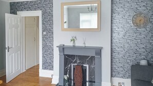 A room with a fireplace, stone wall, and a mirror above it.