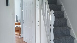 A staircase with a white handrail and carpeted steps leading to a door.