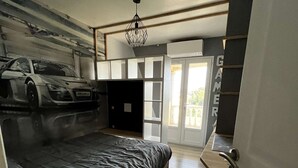 Un dormitorio con cama, armario, escritorio y puerta que da a un balcón.