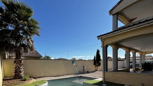 Una piscina con una palmera y un porche techado.