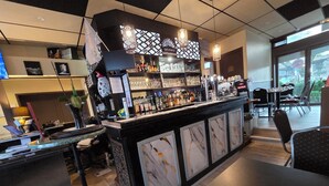 A bar area with a marble counter, shelves with bottles, and a seating area with chairs and a table.