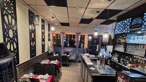 A restaurant with a bar area, tables with chairs, and a counter with a menu.