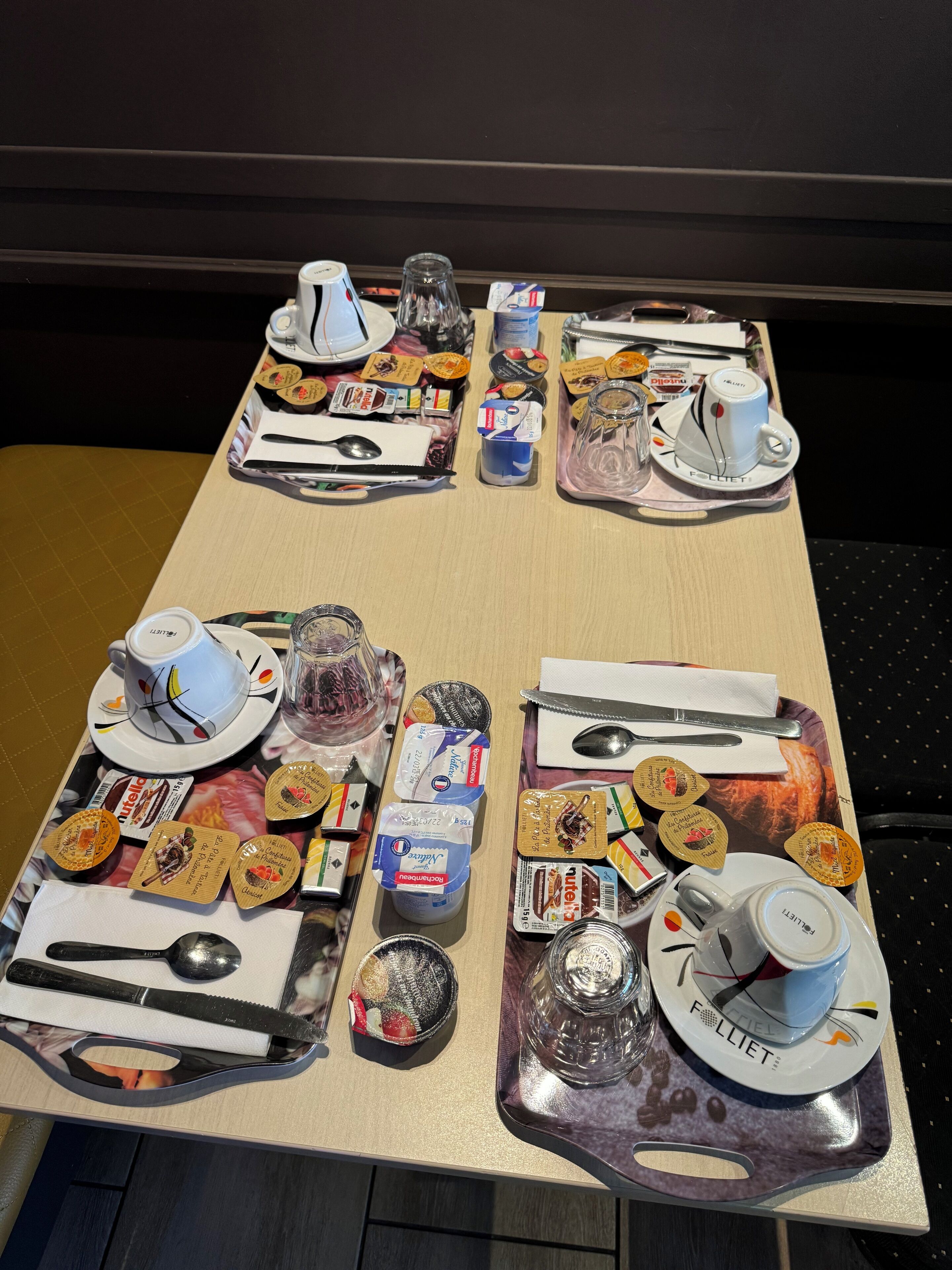 Una bandeja de desayuno con diversas comidas, una taza de café y un vaso de agua sobre una mesa de madera.