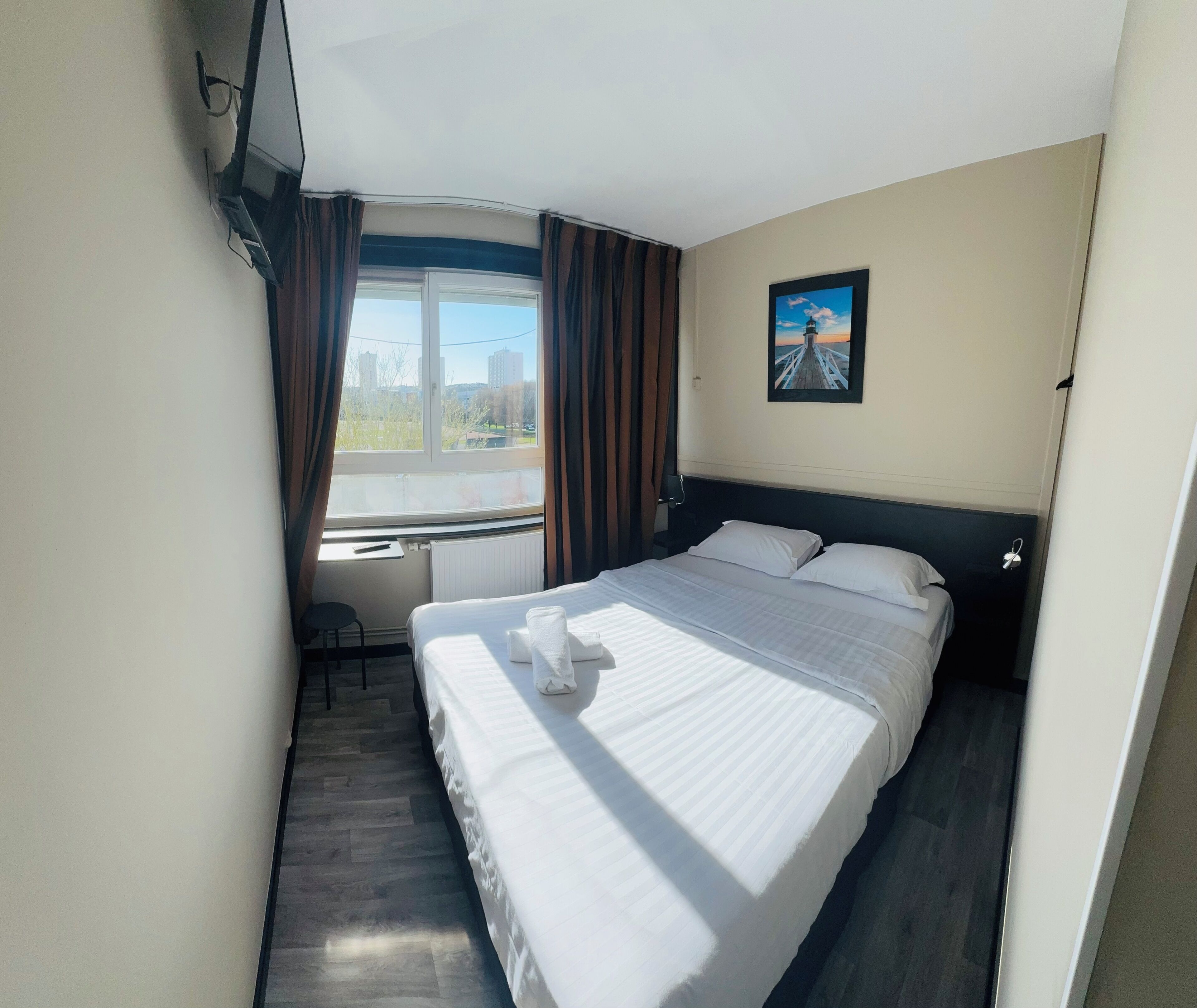 Una habitación de hotel con cama, escritorio y ventana con cortinas.