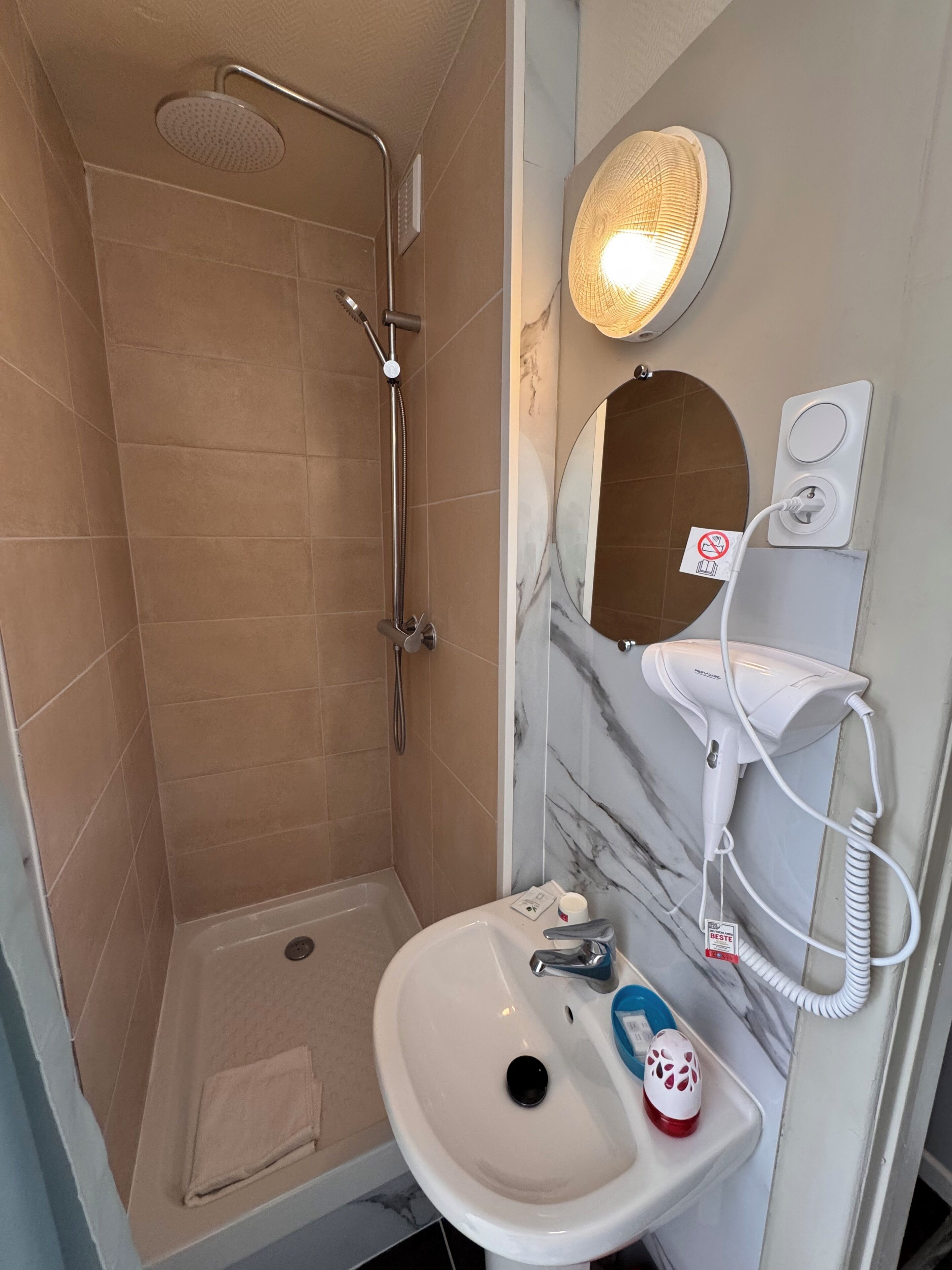 Baño con ducha, lavabo, espejo y secador de pelo.