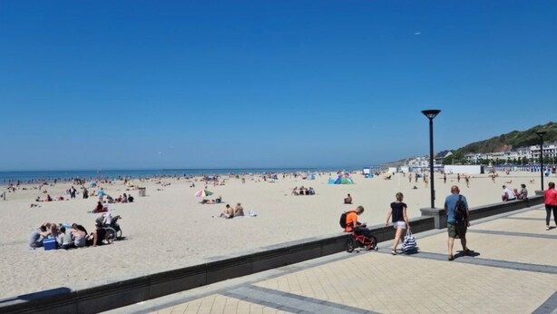 A beach with people relaxing and sunbathing.