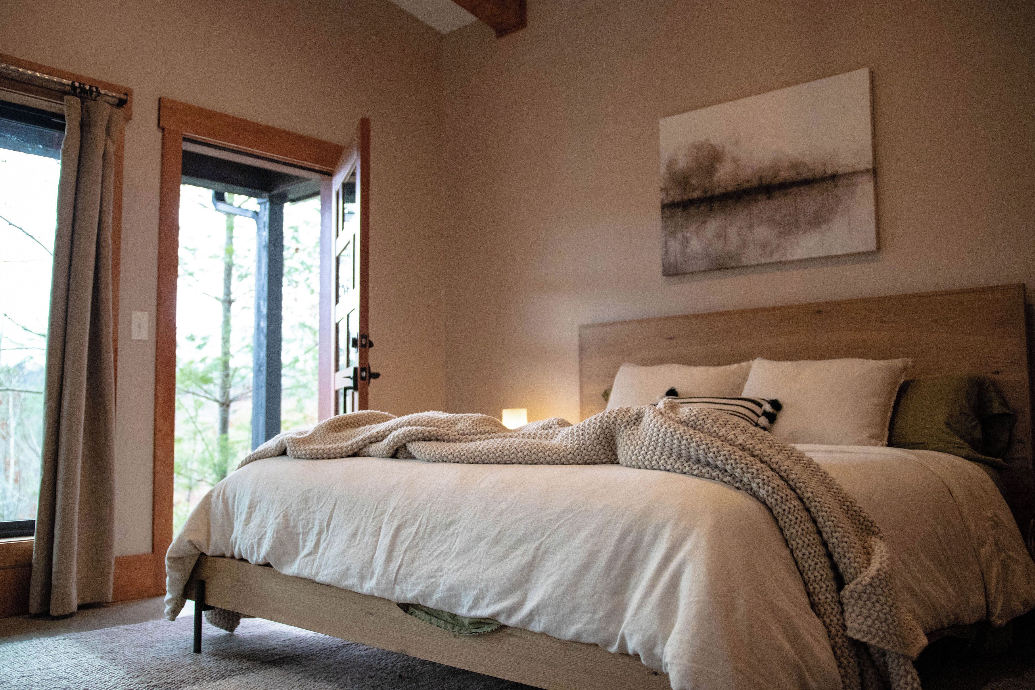 Un dormitorio con una cama grande, cabecera de madera y vistas a través de una puerta abierta.
