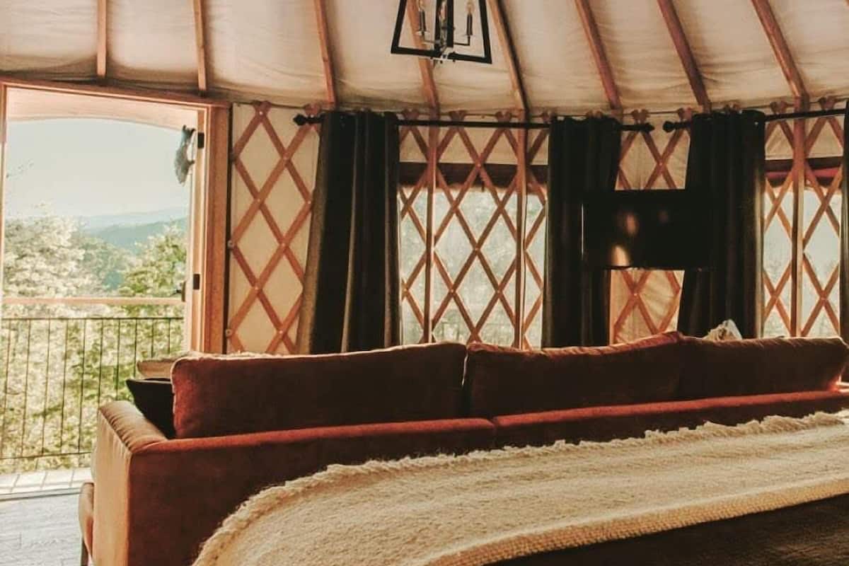 A cozy bed in a tent with a view of the outdoors.