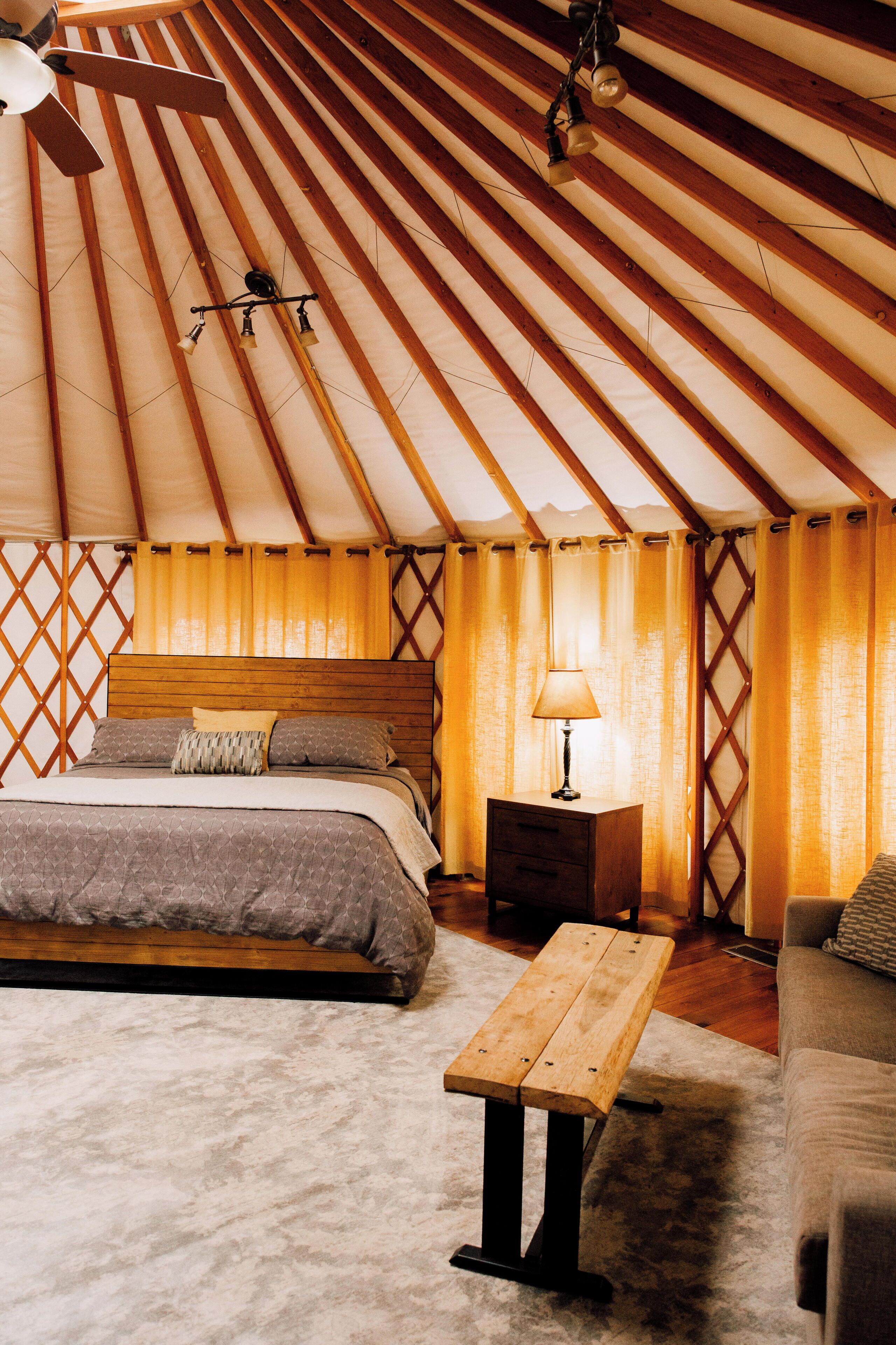A room with a bed, a wooden nightstand, a table, and a ceiling fan.