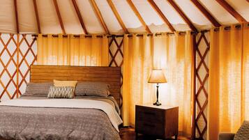 A room with a bed, a wooden nightstand, a table, and a ceiling fan.