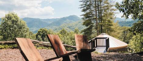 A wooden deck with a rustic gazebo overlooking a mountainous landscape.