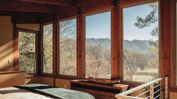 Un dormitorio con un ventanal que ofrece vistas a montañas y árboles.