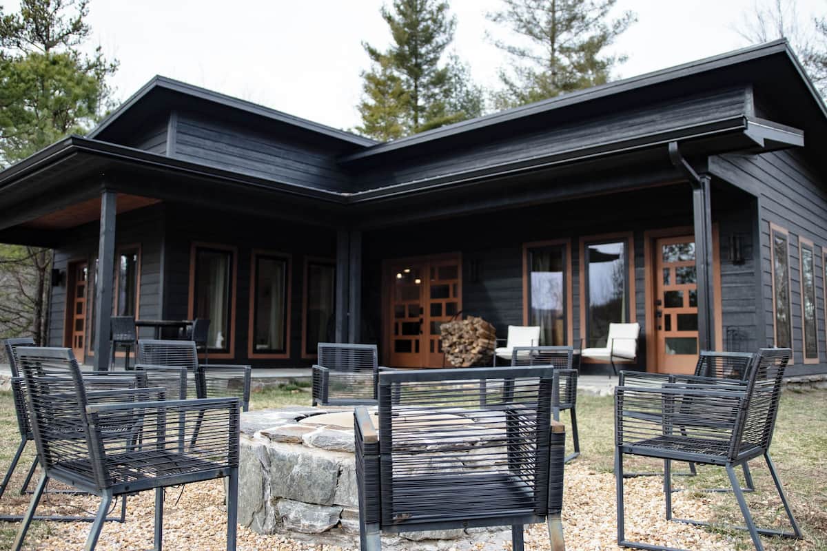 A modern house with a covered patio area featuring outdoor seating and a fire pit.