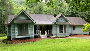 A two-story house with a front porch, a chimney, and a satellite dish.