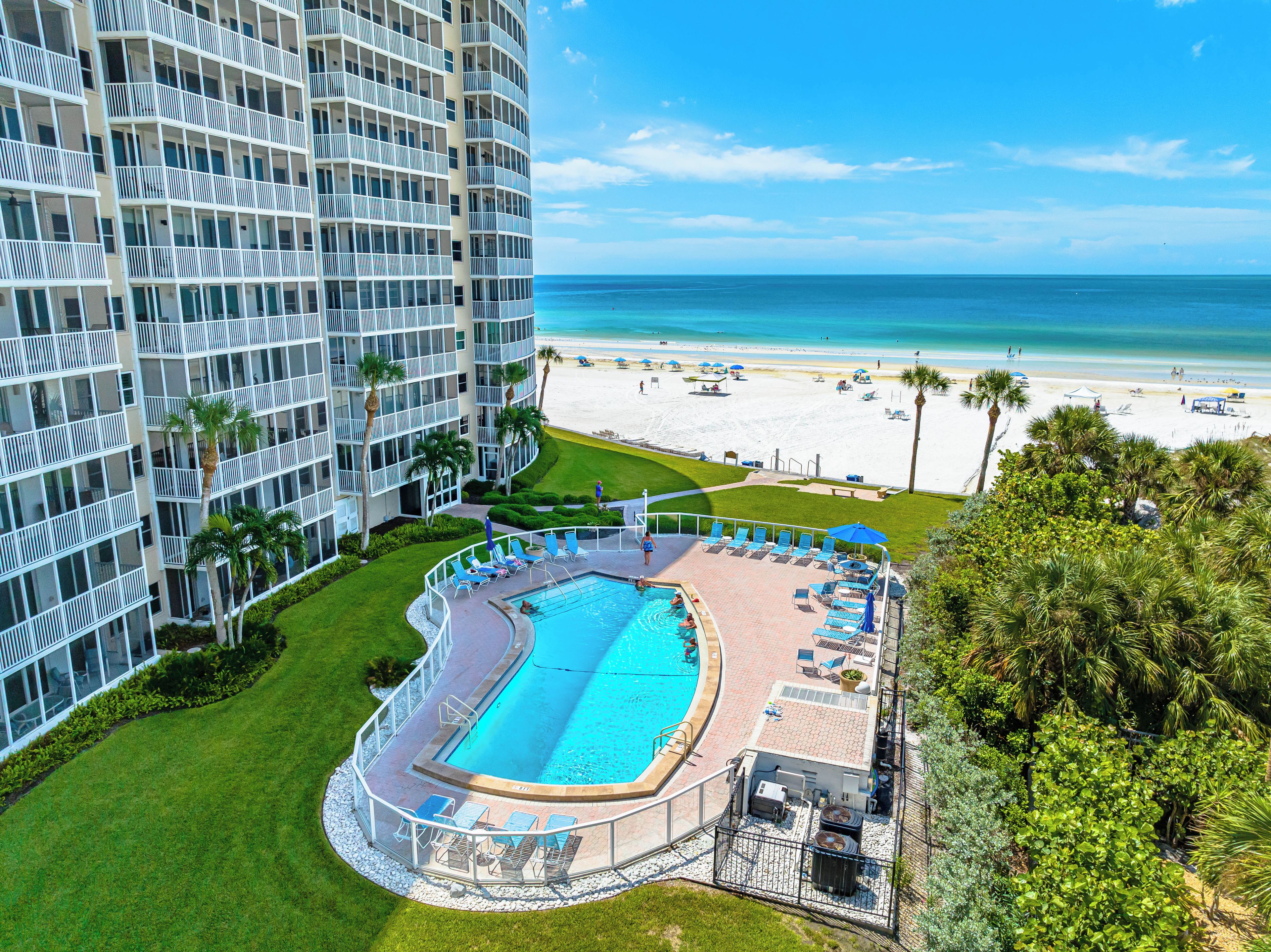 A hotel with a pool, beach view, and a high-rise building.