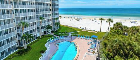 A hotel with a pool, beach view, and a high-rise building.